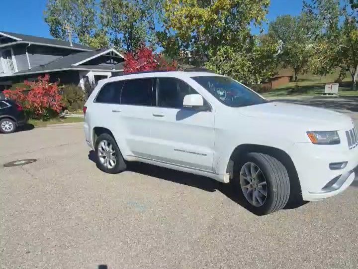 A white Jeep Grand Cherokee parked on a residential street