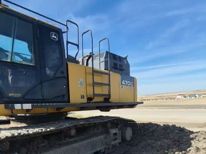A yellow John Deere 470G LC excavator on a gravel yard
